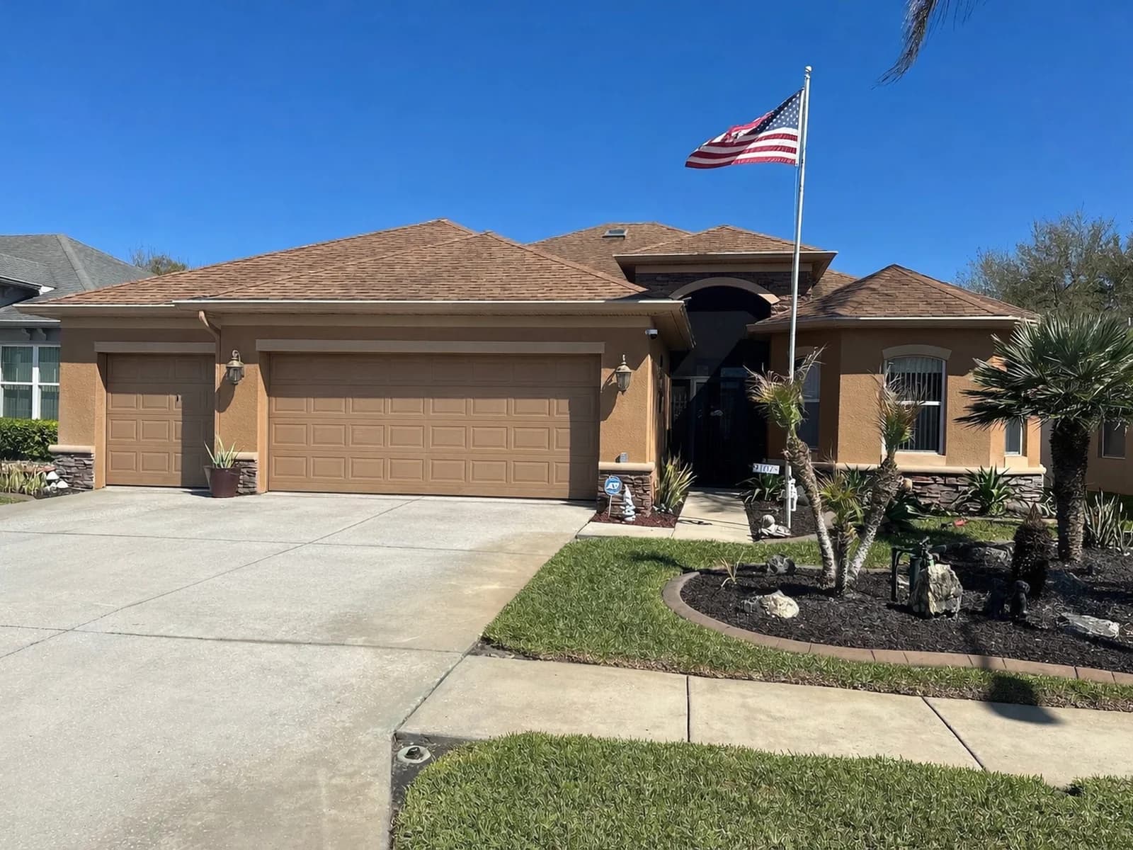 New asphalt shingle roof on a Hernando County stucco home with a 3-car garage and American flag, completed by Protech Roofing