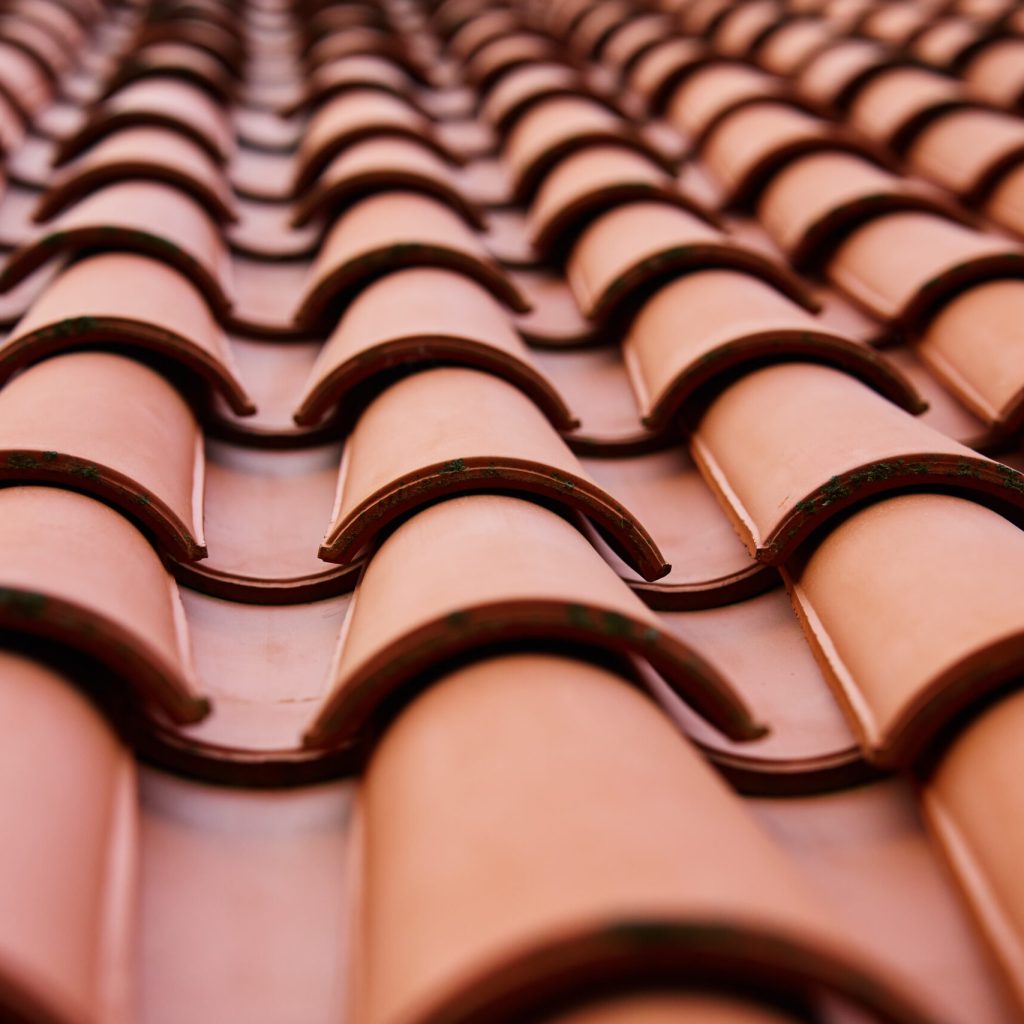 Red Ceramic Roof Tiles Pattern on Building Red ceramic roof tiles covering residential building roof. Tile pattern close-up